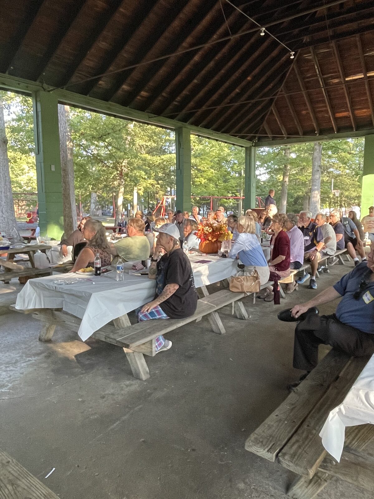 A crowd gathered at picnic tables under the park pavilion