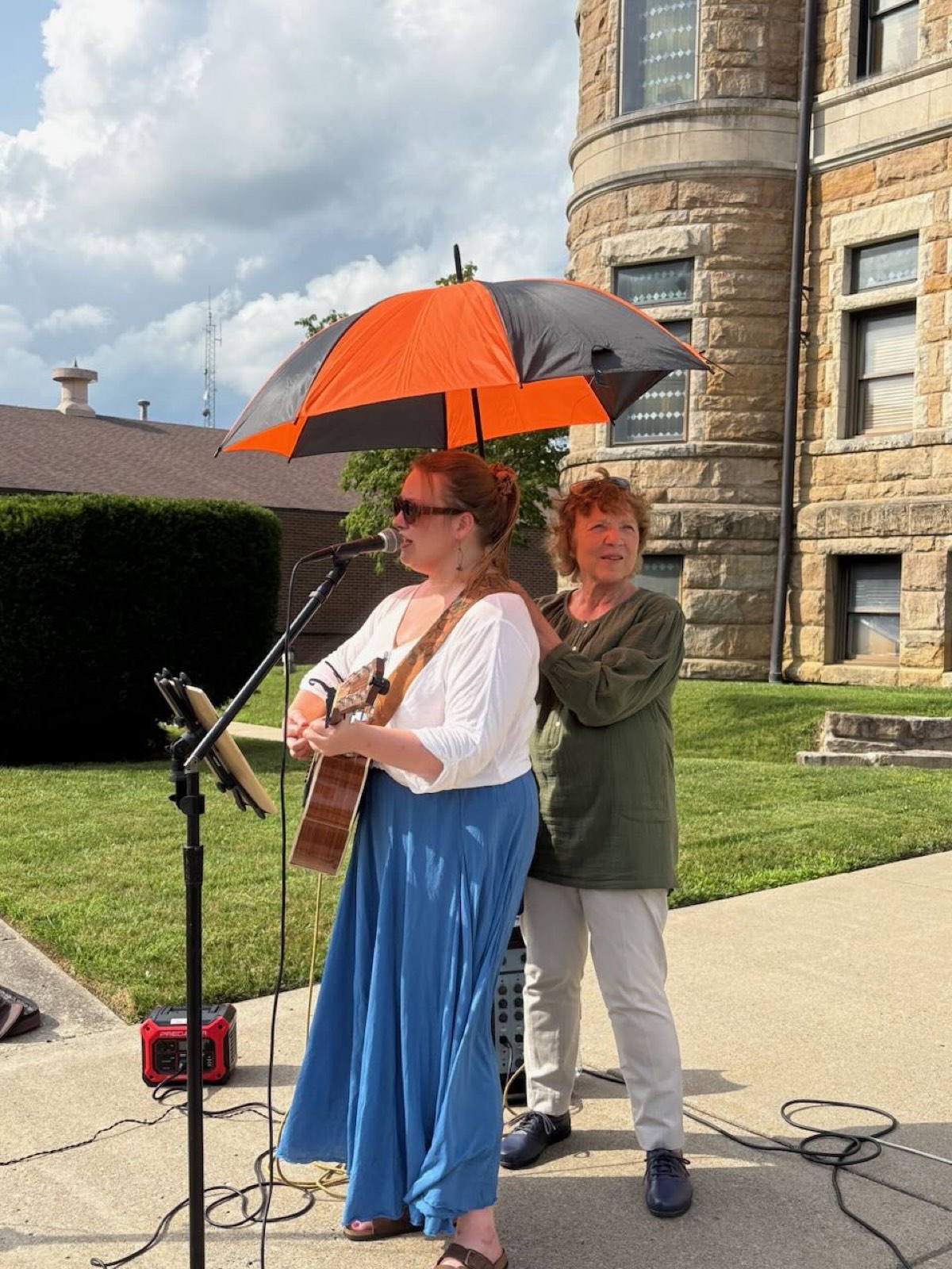 A musician playing guitar and singing on the courthouse lawn